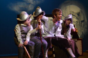 three musketeers, knights, friends, arms around eachother, huddled together, pep talk, encourage, on stage, scene