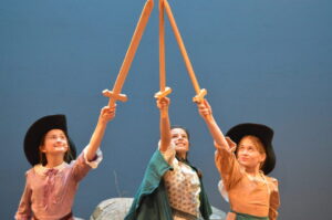 three musketeers, swords, hats, cheers, on stage, together, teamwork, girl power